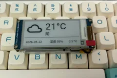 墨水屏云模块摆在键盘上，显示云图标、21°C、阴和日期湿度电压